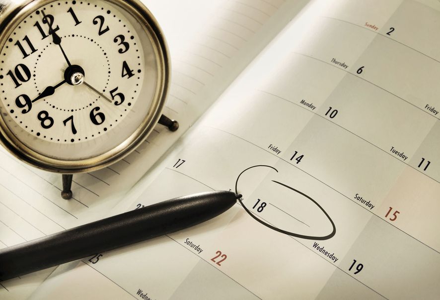 Eine Uhr steht auf einem Kalender, ein Tag wurde mit einem schwarzen Filzstift eingekreist.