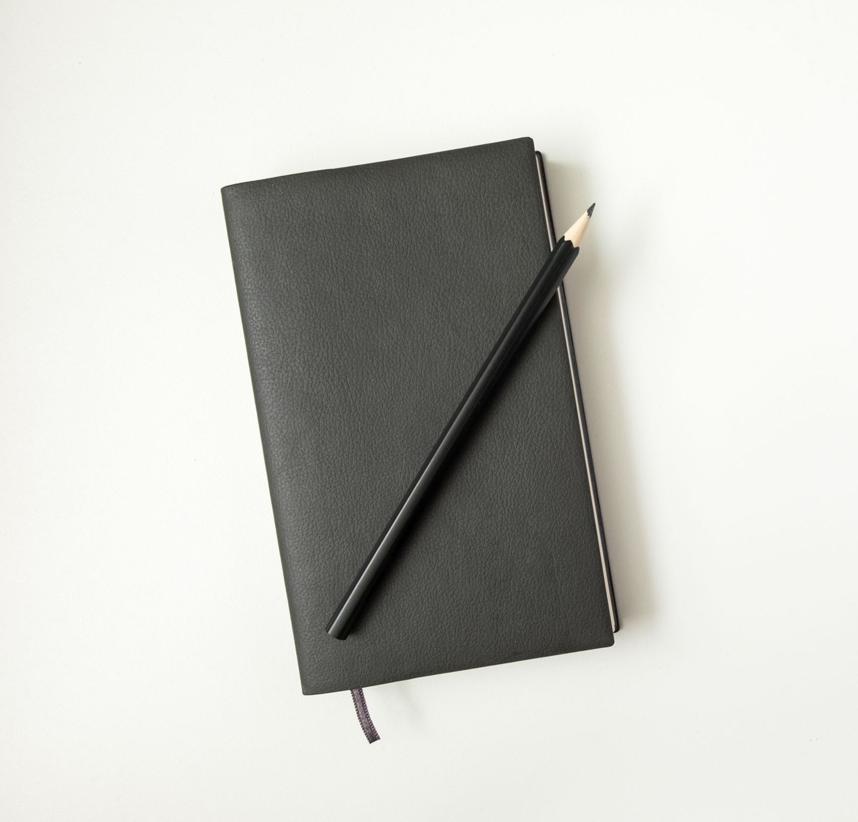 Notizbuch mit schwarzer Lederhülle und ein schwarzer Bleistift